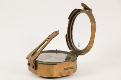 a small brass compass on a white surface