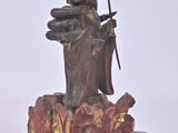 a statue of a woman holding a sword and sitting on a bench