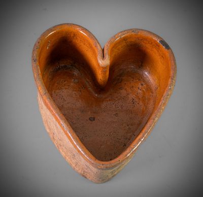 brown ceramic heart shaped bowl sitting on top of a gray surface