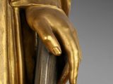 a close up of a gold statue of a person holding a cane