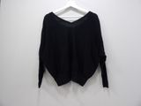 a black sweater hanging on a hanger against a white wall