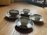 five cups and saucers sitting on a wooden floor
