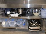 un îlot de cuisine en acier inoxydable sur lequel sont posés des casseroles et des poêles