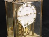 a gold clock that is sitting in a glass case