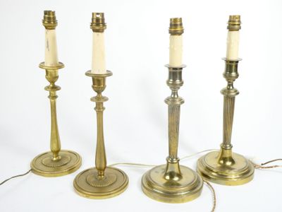 four brass candles are lined up on a white surface