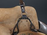 a helmet hanging on the back of a horse ' s saddle