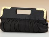 a black purse with a gold handle on a white surface
