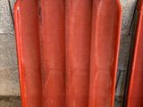 deux morceaux de plastique rouge sur le sol à côté d'un mur de briques