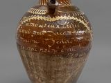 un vieux vase marron portant une inscription sur un fond gris