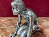 figurine en argent représentant une femme accroupie sur une surface en marbre