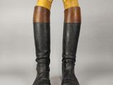 une paire de bottes noires et marron rehaussées de touches jaunes sur fond gris