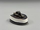 une photo d'une figurine représentant un chien allongé sur un livre