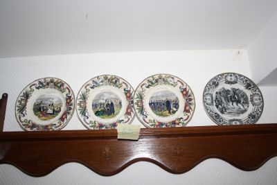 four plates on a shelf with a picture on them