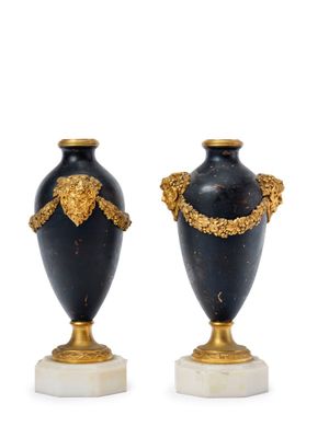 pair of black and gold vases on marble bases on a white background