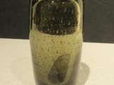 un vase noir et jaune posé sur une table blanche