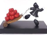 figurine of a man pulling a wheelbarrow with tomatoes on it