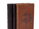 an old book with a leather cover sitting on top of a white surface