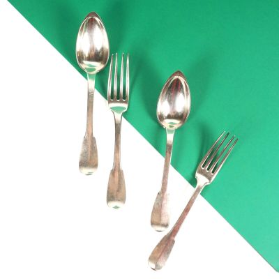 trois cuillères et deux fourchettes sur une table verte et blanche
