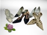 four pairs of women ' s shoes sitting next to a vase of flowers