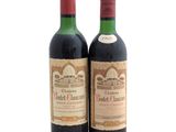 two bottles of red wine sitting next to each other on a white surface