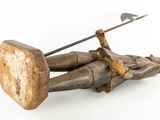 wooden figurine of a man holding a spear and a wooden block