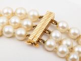 a bracelet with pearls and a gold clasp on a white surface