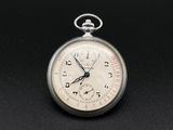 une montre de poche en argent posée sur une surface noire