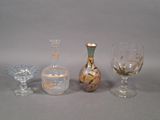 trois vases en verre différents et un verre à vin posés sur une table