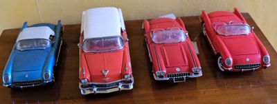 Plusieurs petites voitures sont alignées sur une table devant un mur.