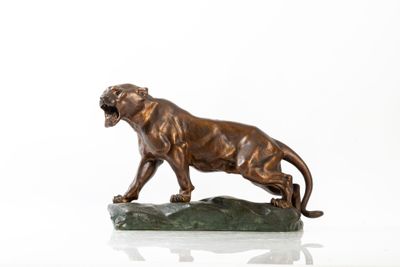 statue en bronze représentant un lion posé sur un rocher, sur un fond blanc
