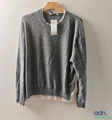 a grey sweater hanging on a hanger against a white wall