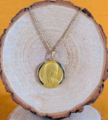 a close up of a gold necklace with a picture of a woman on it