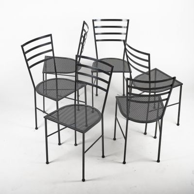 three black metal chairs and a table on a white background