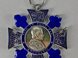 une image représentant une médaille bleue et argentée sur laquelle figure le portrait d'un homme