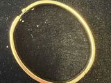 a close up of a gold bracelet on a black surface