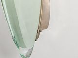 a green glass vase hanging on a wall next to a white wall