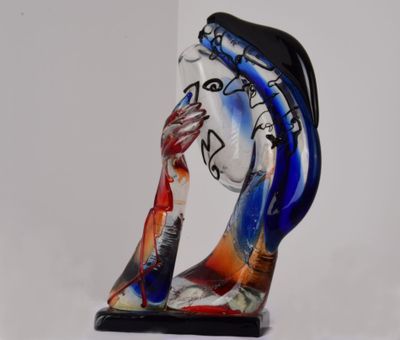 une sculpture en verre représentant une femme vêtue d'une robe bleue et rouge