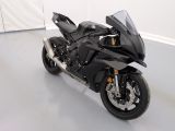 une moto noire garée dans une pièce aux murs blancs