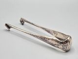 a pair of silverware tonges sitting on top of a white surface