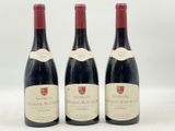 trois bouteilles de vin rouge posées sur une table blanche