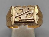 a close up of a gold signet ring on a white stand