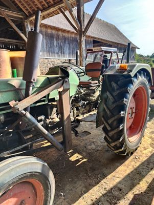 a tractor that is parked in the dirt by a building