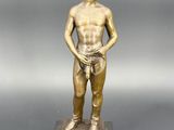 statue en bronze représentant un homme coiffé d'un chapeau et tenant un lasset