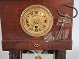 a small wooden clock with a key on it