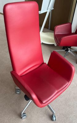 une chaise de bureau rouge posée au milieu d'une pièce