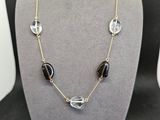 un collier composé de perles en verre noires et transparentes montées sur une chaîne en or