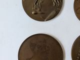 three bronze medals of a woman and a man on a white surface