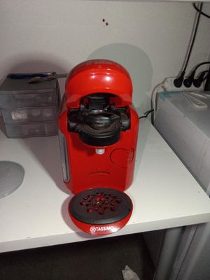 une cafetière rouge posée sur un plan de travail blanc