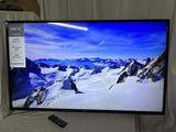 La télévision à écran plat est posée sur un lit, avec une télécommande à côté.