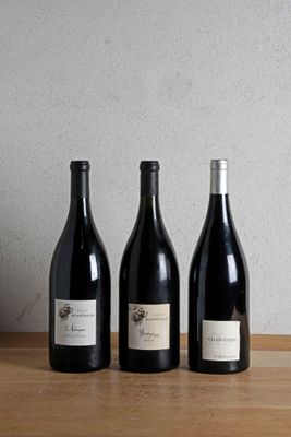 three bottles of wine are lined up on a wooden table